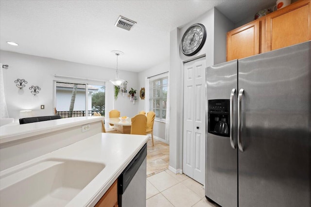 kitchen with sink, hanging light fixtures, light tile patterned floors, a textured ceiling, and stainless steel appliances