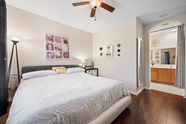 bedroom with ceiling fan, dark hardwood / wood-style flooring, sink, and ensuite bath