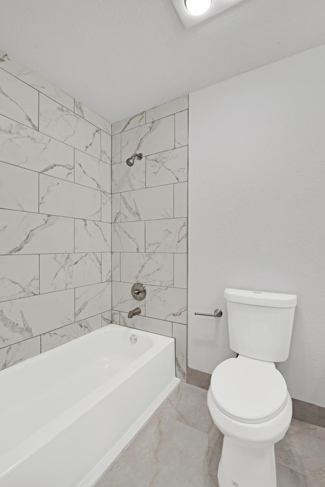 bathroom featuring tiled shower / bath combo and toilet