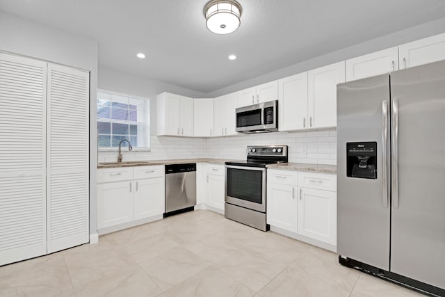 kitchen featuring stainless steel appliances, sink, white cabinets, and backsplash