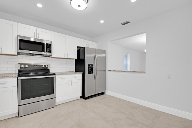 kitchen featuring white cabinetry, stainless steel appliances, light stone counters, and tasteful backsplash