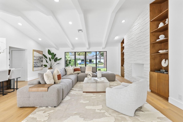 living room featuring a fireplace, lofted ceiling with beams, and light wood-type flooring