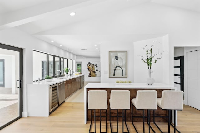 kitchen with lofted ceiling, sink, a center island, and light wood-type flooring