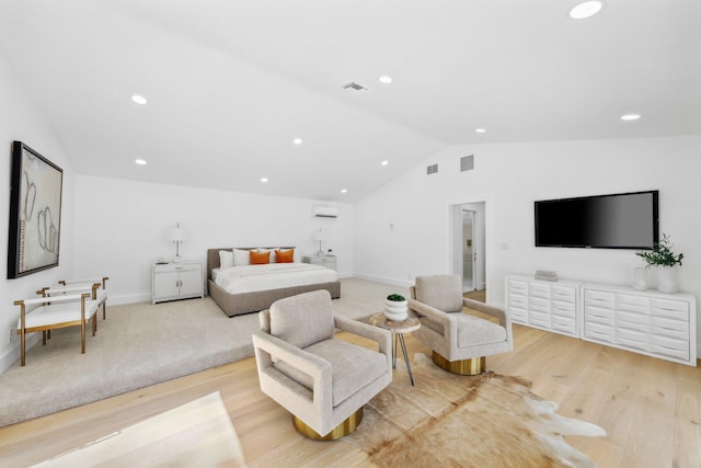 bedroom featuring vaulted ceiling, a wall unit AC, and light wood-type flooring