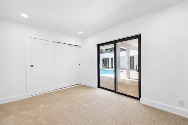 unfurnished bedroom featuring light carpet, access to exterior, and a closet