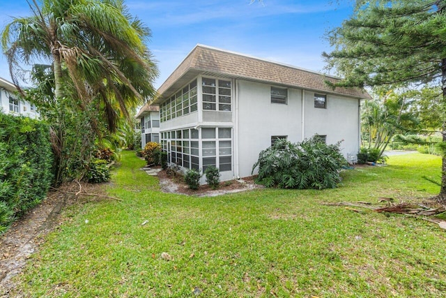 view of property exterior with a sunroom and a lawn