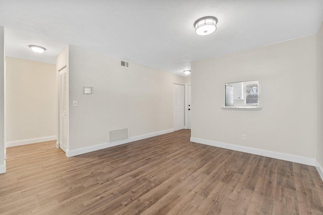 spare room featuring wood-type flooring and a textured ceiling