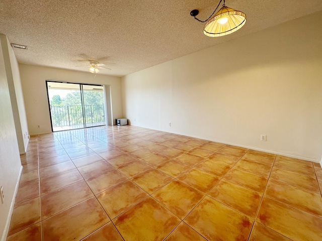 tiled empty room with ceiling fan and a textured ceiling