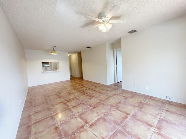 tiled empty room featuring ceiling fan and a textured ceiling