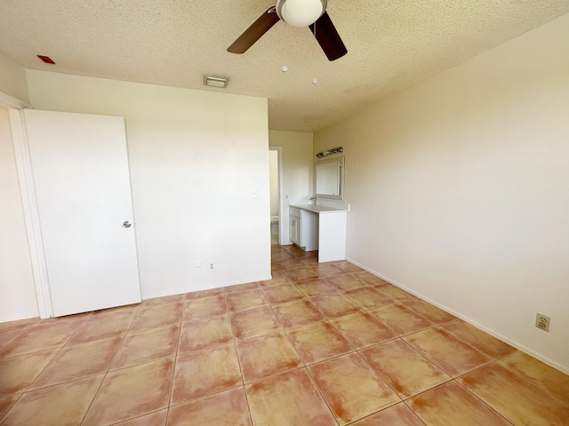 empty room featuring light tile patterned flooring, ceiling fan, and a textured ceiling