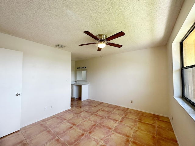 unfurnished room with ceiling fan, light tile patterned floors, and a textured ceiling