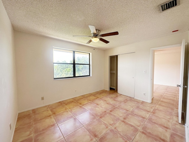 unfurnished bedroom featuring light tile patterned floors, a textured ceiling, and ceiling fan