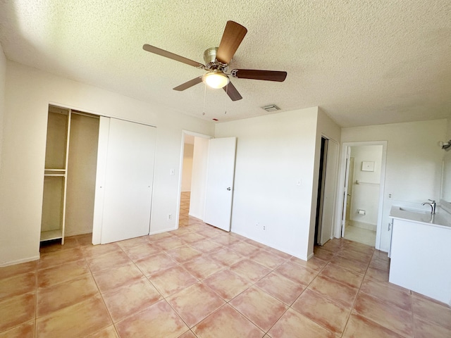 unfurnished bedroom with sink, a textured ceiling, ceiling fan, and light tile patterned flooring