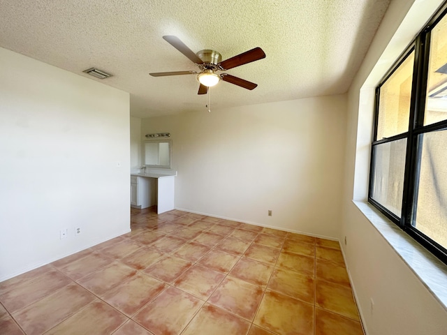 tiled spare room with ceiling fan and a textured ceiling