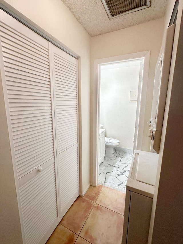 hall featuring washer / dryer and light tile patterned flooring