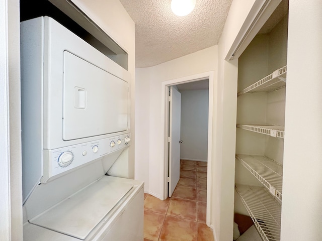 washroom with stacked washer and clothes dryer, a textured ceiling, and light tile patterned floors