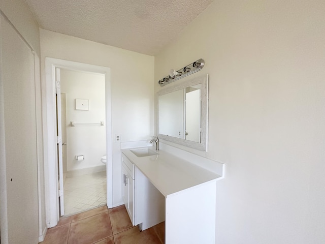 bathroom with tile patterned flooring, vanity, toilet, and a textured ceiling