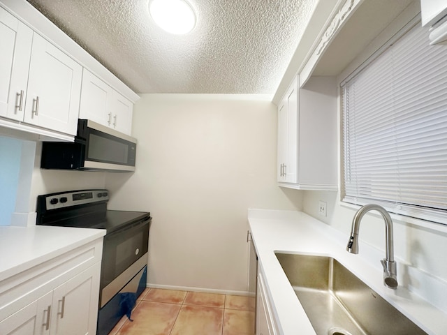 kitchen with sink, stainless steel appliances, a textured ceiling, white cabinets, and light tile patterned flooring