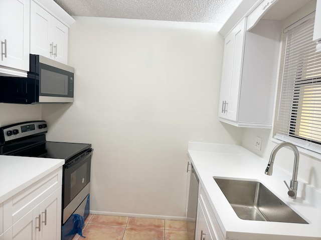 kitchen with sink, white cabinetry, a textured ceiling, light tile patterned floors, and appliances with stainless steel finishes