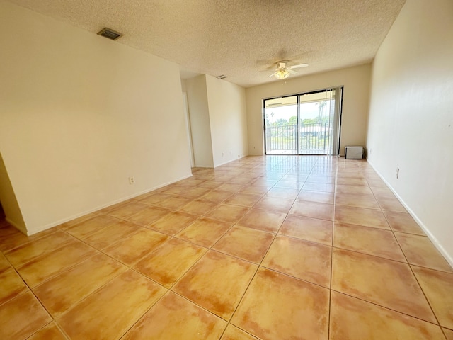 empty room featuring ceiling fan, light tile patterned floors, and a textured ceiling