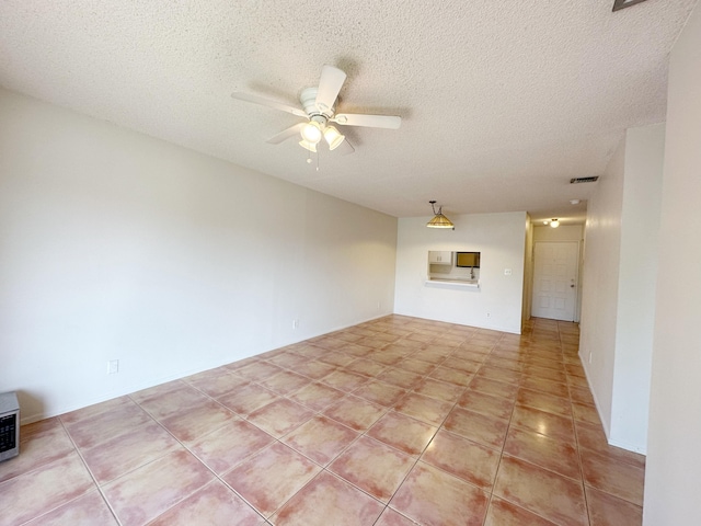 spare room featuring ceiling fan, a textured ceiling, and light tile patterned flooring