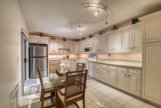 kitchen featuring light tile patterned floors, sink, stainless steel appliances, track lighting, and a textured ceiling