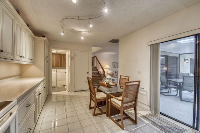 dining space featuring washing machine and dryer, a textured ceiling, and light tile patterned floors