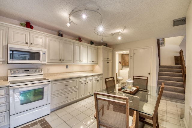 kitchen with electric stove, washer / dryer, a textured ceiling, and light tile patterned flooring