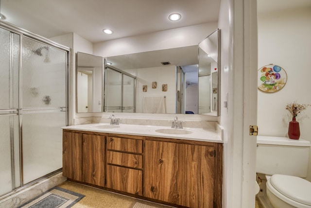 bathroom with vanity, a shower with door, and toilet