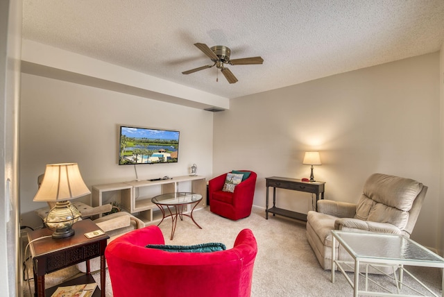 living room featuring ceiling fan, carpet floors, and a textured ceiling