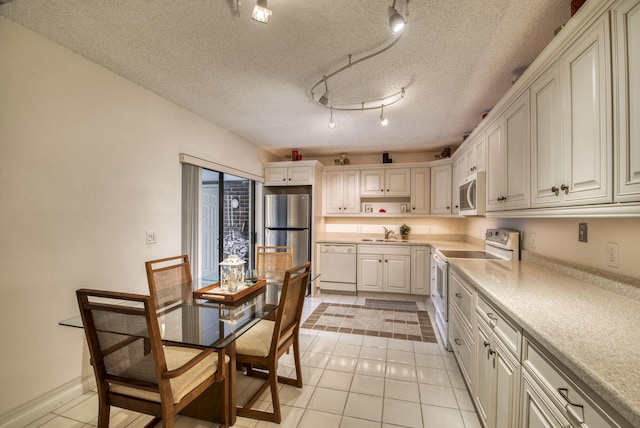 kitchen featuring light tile patterned flooring, sink, white cabinetry, a textured ceiling, and white appliances