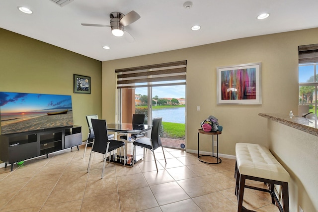 dining room with a water view, ceiling fan, a healthy amount of sunlight, and light tile patterned flooring