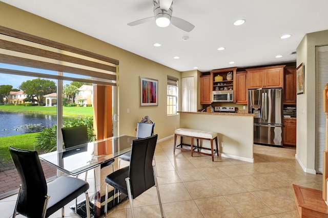 tiled dining space featuring a water view and ceiling fan