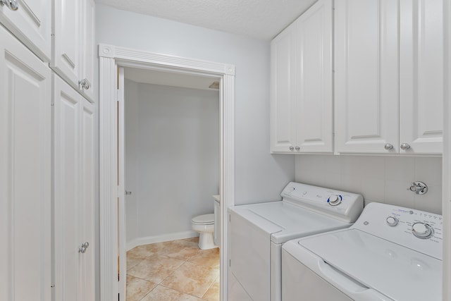 laundry area featuring light tile patterned floors, washer and clothes dryer, cabinets, and a textured ceiling