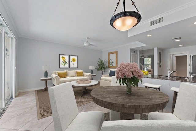 dining area with sink, ornamental molding, light tile patterned floors, ceiling fan, and a textured ceiling