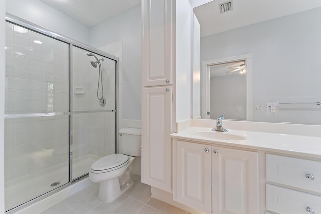 bathroom featuring vanity, a shower with door, tile patterned floors, and toilet