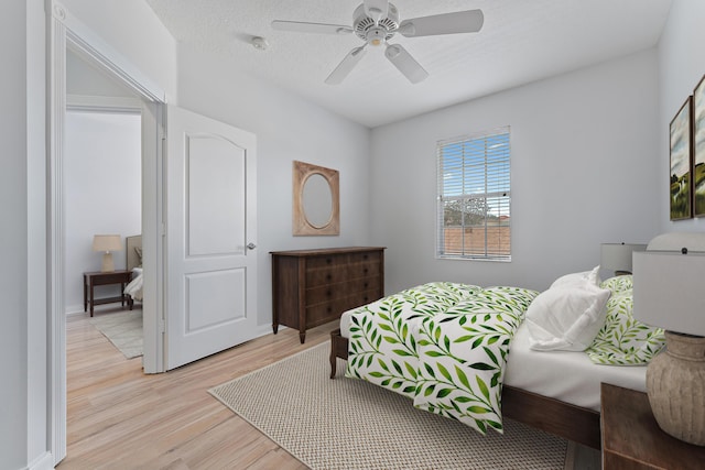 bedroom with a textured ceiling, ceiling fan, and light hardwood / wood-style flooring