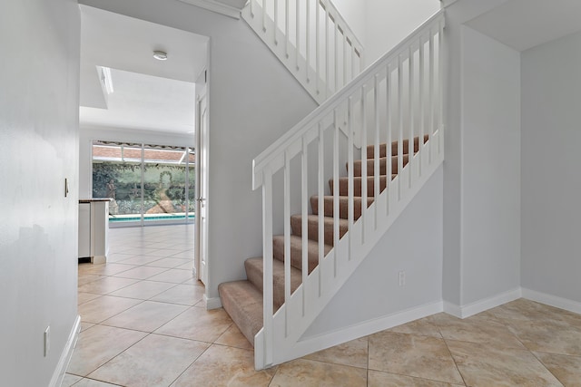 stairway featuring crown molding and tile patterned flooring