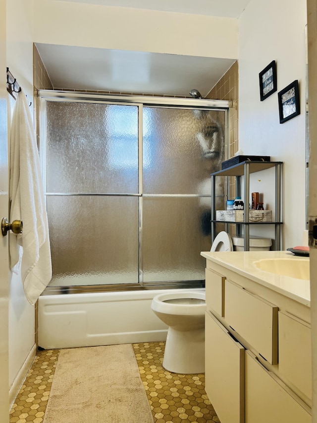 full bathroom featuring toilet, tile patterned floors, vanity, and bath / shower combo with glass door