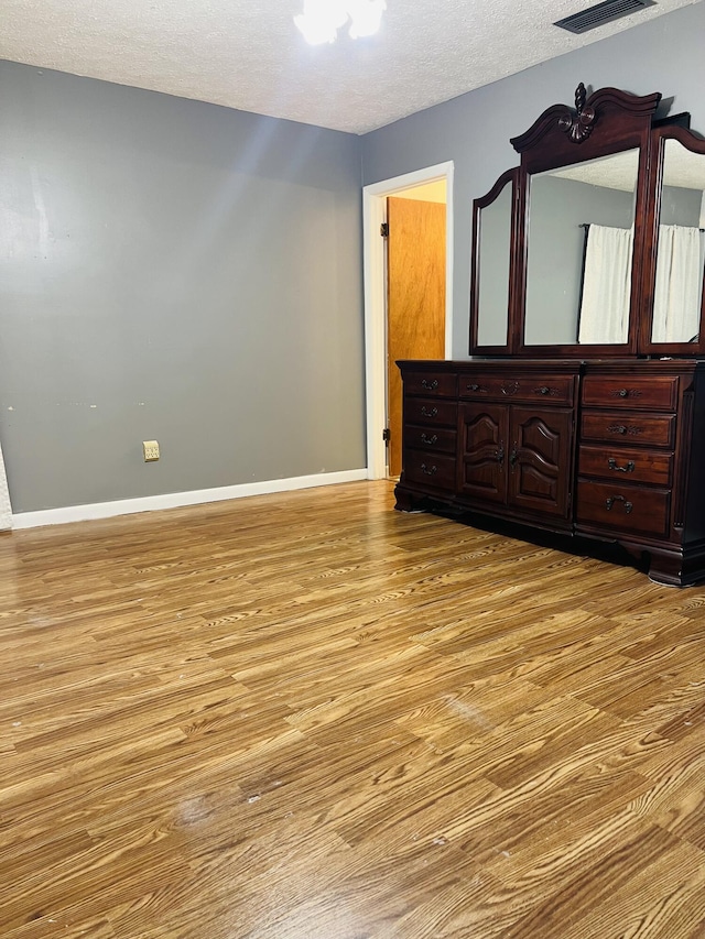 bedroom with a textured ceiling and light wood-type flooring