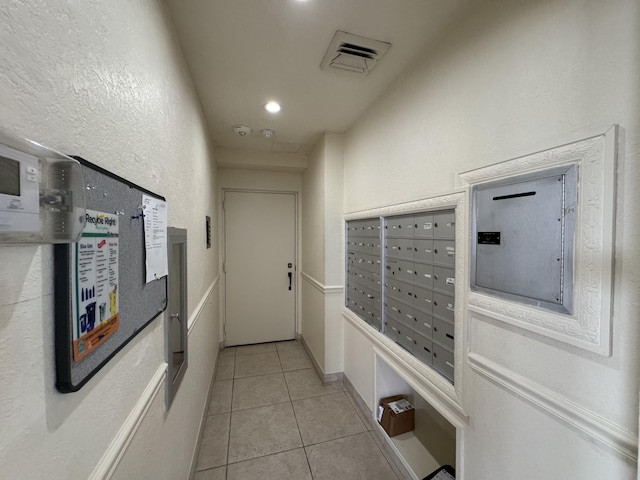 hall with light tile patterned flooring and a mail area