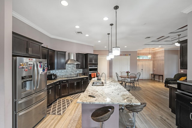 kitchen with a breakfast bar, sink, a large island, stainless steel appliances, and wall chimney exhaust hood