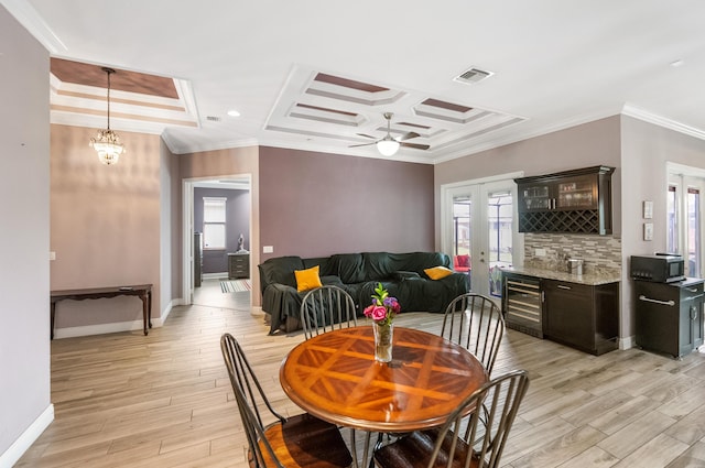 dining room with coffered ceiling, ornamental molding, beverage cooler, and light hardwood / wood-style floors