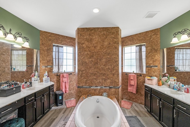 bathroom featuring wood-type flooring, tile walls, and a tub to relax in