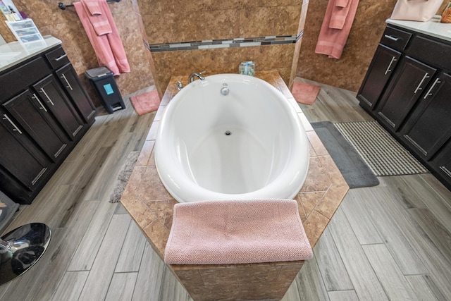 bathroom featuring vanity, tiled bath, and tile walls