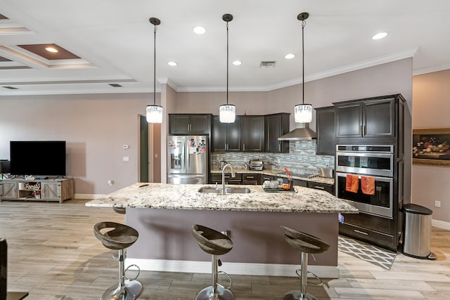 kitchen with a breakfast bar, sink, decorative light fixtures, an island with sink, and stainless steel appliances