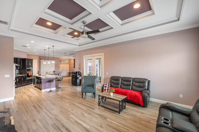 living room with ornamental molding, coffered ceiling, and light wood-type flooring