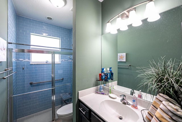 bathroom featuring vanity, toilet, a shower with door, and a textured ceiling