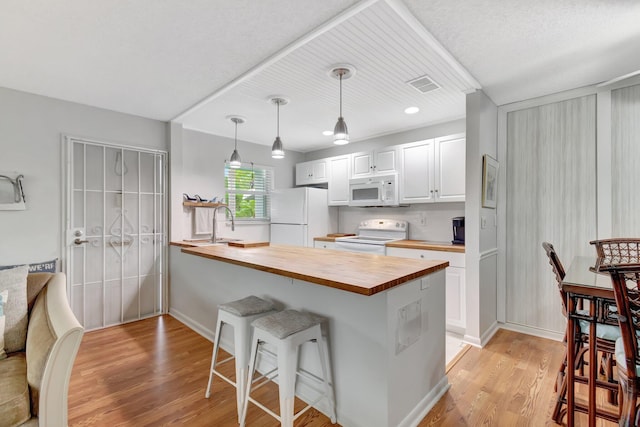 kitchen with white appliances, wooden counters, a breakfast bar, hanging light fixtures, and white cabinets