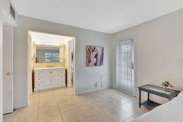 doorway to outside featuring light tile patterned flooring, sink, and a textured ceiling